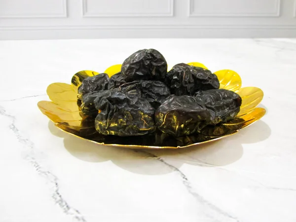 Parlak altın bir tabağa yerleştirilmiş Ajwa ağaçları, besin değeri yüksek sağlıklı meyveler, genellikle Ramazan 'da keyif alırlar..