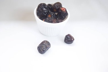 Beyaz arka planda bir kasede kurutulmuş hurmalar, oruç tutmak için kullanılır.