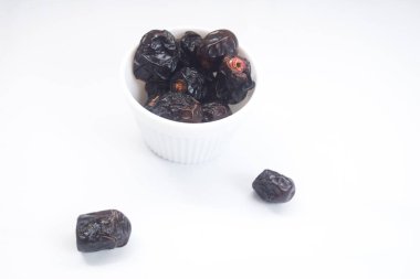 Beyaz arka planda bir kasede kurutulmuş hurmalar, oruç tutmak için kullanılır.