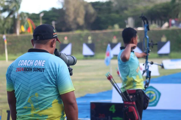 Banda Aceh, Indonesia - September 19, 2025: The coach uses a spotting scope to check accuracy, while the archer is in full draw position with a modern compound bow