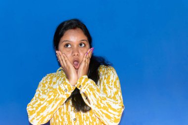 Hintli kadın şaşırdı ve şok oldu. Elleriyle yanaklarını tuttu. Kıvırcık saçlı, şaşkın bakışlı güzel bir kız. Ürününüzü sunuyorum. Etkileyici yüz ifadeleri. Seçici odak.