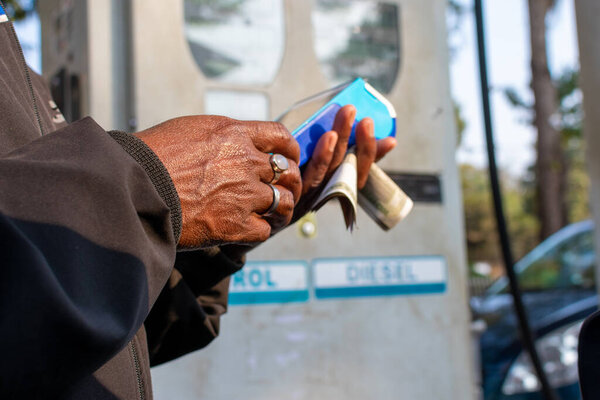 Close up of hand using credit card swiping machine to pay in petrol pump in India. Man entering credit card code in swipe machine. Online payment, financial inclusion concept.