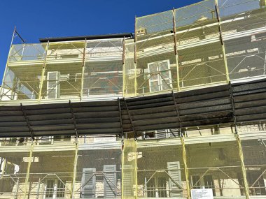 İtalya 'da iskelesi yenilenen eski bir bina. İskele ve sarı güvenlik ağıyla restore edilen tarihi İtalyan binası cephesi.