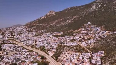Flight of a drone over the coastal town of Kalkan, Antalya, Turkey. Panoramic view of the city buildings in the mountains