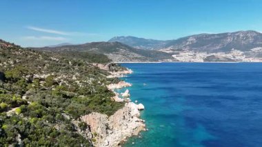 TurquoisAerial panorama of the Mediterranean Sea along the coast of Kalkan, Turkey. Vibrant blue waters, rocky shores, and mountains on the horizon create a picturesque landscape. Perfect for travel, summer vacation, ecotourism, and Turkish Riviera
