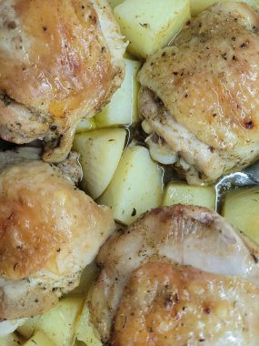 Kızarmış tavuk budu ve baharatlı patatesle yakından çekilmiş bir fotoğraf. Tabakta, lezzetli ve rahatlatıcı bir yemek sunan altın sarısı tavuk ve taze patatesler yer alıyor..