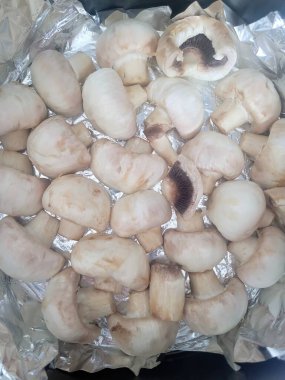 Folyoda pişmeye hazır taze beyaz mantarların yakın çekimi. Görüntü mantarların doğal dokusunu vurgular, basit güzelliklerini ve sağlıklı beslenme potansiyellerini vurgular..