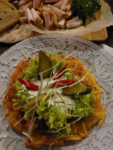 Pastırmalı, marullu, turşulu, kırmızı biberli ve beyaz tabakta ekşi kremalı leziz patatesli gözleme, yanında da pastırma, maydanoz ve siyah ekmek. 