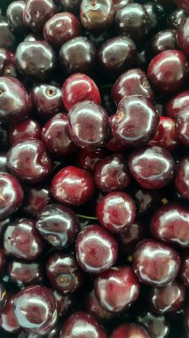 Close-up shot showcasing the rich, deep red color and shiny surfaces of fresh cherries, highlighting their plumpness and inviting texture, perfect for summer fruit themes 