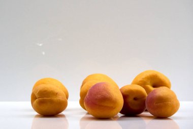 Ripe apricots on a white surface are photographed against a light background, creating a vivid and enticing image for healthy eating and fruit-themed concepts  