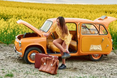 Genç bir kadın, sarı bir çiçek tarlasında eski bir arabayla yolculuğunu bölerek ayakkabılarını giyer, eski tarz ve seyahat aşkını gözler önüne serer.. 