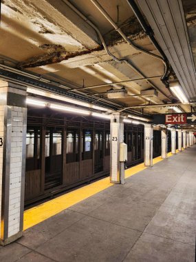 Empty New York City subway station with train waiting on platform.