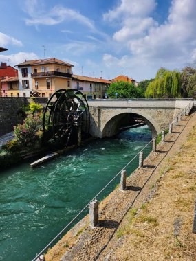Wide angle view of a riverside bridge and green surroundings.