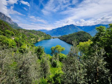 Turquoise colored lake surrounded by green hills.