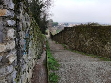 Narrow stone path running between old masonry walls in a historic village.
