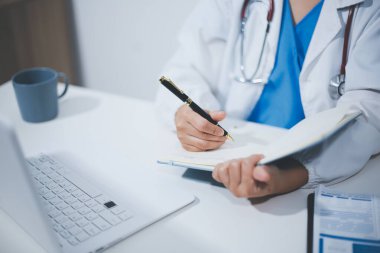 Doktorun odasında dizüstü bilgisayarla çalışan orta yaşlı bir kadın doktor.