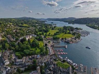 A picturesque lakeside town reveals a vibrant marina, lush landscapes, and charming architecture under a clear sky during the afternoon, creating a tranquil atmosphere.