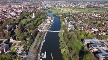 Aerial view reveals a picturesque river winding through a tranquil landscape. Lush trees line the banks, while quaint houses dot the surroundings, showcasing natural beauty.