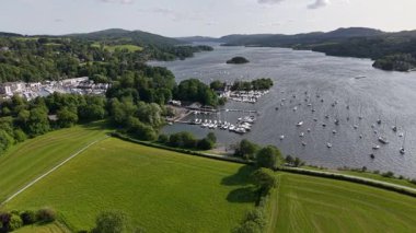 This captivating aerial view showcases a beautiful lake bordered by rolling green hills and dotted with boats.