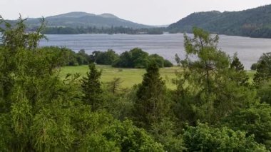 A breathtaking view of a peaceful lake framed by dense trees and rolling hills, highlighting natures beauty in a quiet setting. Ideal for relaxation and contemplation.