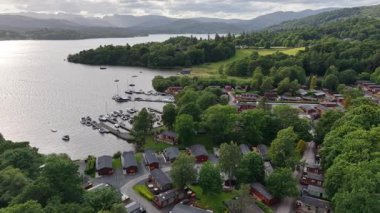 Enjoy a breathtaking aerial perspective showcasing cozy cabins nestled among vibrant trees along a serene lake. This tranquil setting captures the beauty of nature and relaxation.