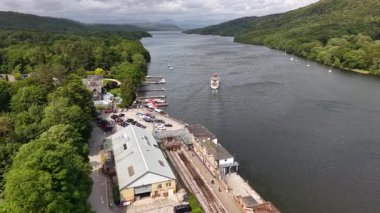 This captivating landscape showcases a river flowing peacefully amid vibrant greenery. Boaters enjoy their day on the water while historic buildings line the shore, merging nature with heritage.