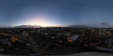 A panoramic view presents the city skyline at dusk. Buildings of various styles contrast against the fading light, with clouds scattered in the sky, creating a tranquil evening atmosphere.