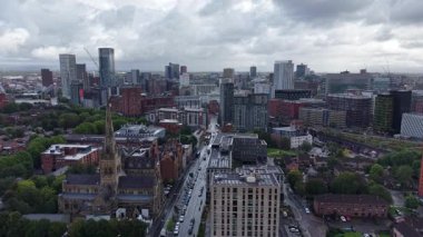 Experience the dynamic skyline of Manchester from above, showcasing a blend of modern buildings and greenery against overcast skies. This view captures the essence of urban life.