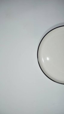 Siyah kenarlı, sade, beyaz bir plaka çerçevenin altına, açık mavi bir arkaplan karşısında, minimalist bir estetik sunar..