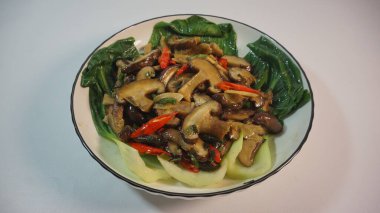 Mantar ve sebze karışımından oluşan canlı ve iştah açıcı bir yemek, bir kasede ustaca hazırlanmış, sağlıklı ve görsel olarak çekici bir yemek sunuyor..