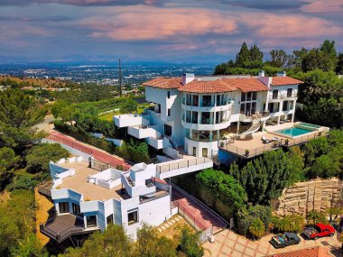 Geniş manzaralı lüks yamaç köşkü, birden fazla katlı, havuzlu ve benzersiz mimari tasarımı var..