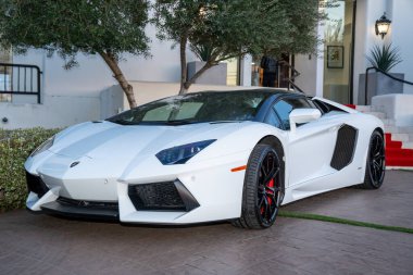 Bir binanın önüne park etmiş el değmemiş beyaz bir Lamborghini Aventador Roadster. Lüks spor araba, güneşli bir gün..