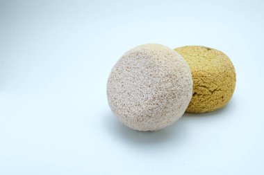 İki doğal banyo süngeri, sarı ve beyaz renkte, temiz beyaz arka planda yan yana yerleştirilmiş. Hijyen, cilt bakımı, banyo malzemeleri, çevre dostu yaşam tarzı, sürdürülebilirlik için uygun.