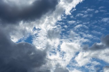 Koyu fırtına bulutları ve açık kümülüs bulutlarının karışımı ile dramatik bir gökyüzü, parlak mavi gökyüzünün parçalarını ortaya çıkarıyor. Zıt dokular ve aydınlatma değişen hava ve dinamik atmosferi gösteriyor..