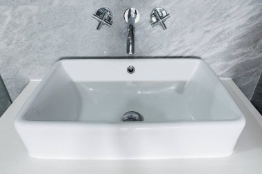 Seramik beyaz leğen banyoda tezgahın üstünde.