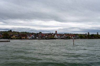Almanya 'nın Hagenau şehrinin tarihi şehir merkezini gösteren Constance Gölü' nden bir görüntü. Su üzerinde dramatik bulutlu bir gökyüzü ve fırtınalı bir hava var..