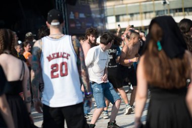 07 / 25 / 2025 - Bulgaristan 'ın Plovdiv kenti: Bir açık hava konseri sırasında sahnenin yakınındaki pogo dansı hareketine katılan günlük kıyafet ve bant gömlekli katılımcıların canlı atmosferini yakaladığı enerjik bir canlı müzik festivali sahnesi.