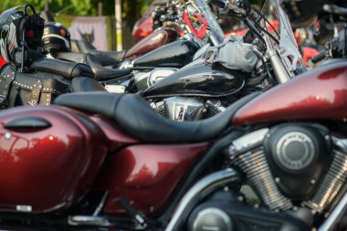 Park halindeki kruvazör motosikletleri krom renkli V-ikiz motorlar, parlak kırmızı tank, deri eyer çantası ve bisiklet yarışındaki koltuklarda dinlenen kasklar..