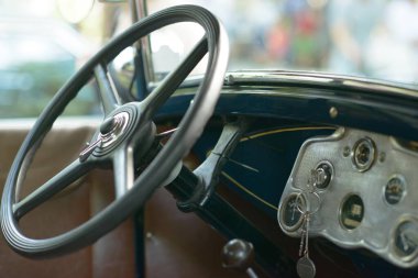 Cilalanmış antika direksiyon, krom korna düğmesi ve klasik bir otomobil fuarında restore edilmiş eski bir arabanın içinde sallanan kontak anahtarı olan sanat deco göstergeleri..