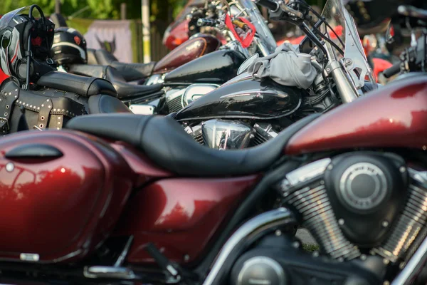 Park halindeki kruvazör motosikletleri krom renkli V-ikiz motorlar, parlak kırmızı tank, deri eyer çantası ve bisiklet yarışındaki koltuklarda dinlenen kasklar..