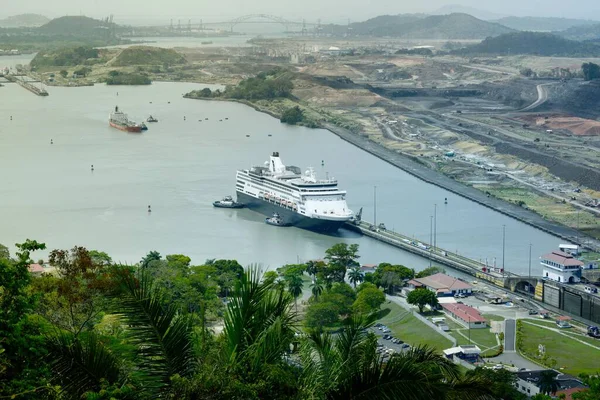 Panama Kanalı 'nın tropikal bitki örtüsü, inşaat arazisi ve kanal boyunca uzanan altyapı ile çevrili bir yolcu gemisinin kilit odasına girdiği hava manzarası..