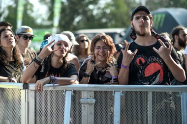 Filibe, Bulgaristan - 07 / 25 / 2025: Bulgaristan 'ın Plovdiv kentindeki Hills of Rock barikatının yakınlarında poz veren festival taraftarları kaya el hareketleri yaparak yaz müzik festivali atmosferinin keyfini çıkarıyorlar.