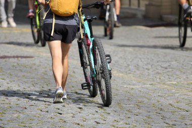 Sırt çantalı genç adam şehir caddesinde bisiklet sürüyor, yakın plan.