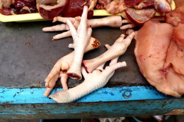 Geleneksel bir pazarda taze çiğ tavuk ayağı satılıyor. Lezzetli ve besleyici yemekler için temel bir bileşen..
