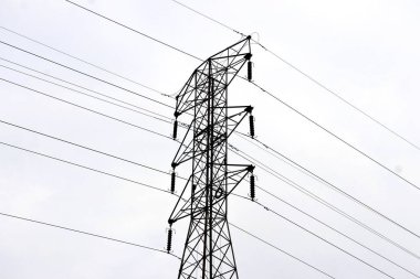 Gökyüzü boyunca uzanan çoklu güç hatları olan yüksek voltajlı bir elektrik iletim kulesi. Çelik kafes yapısı modern enerjiyi temsil eden güçlü ve simetriktir..