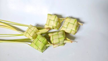 Ketupat, Hindistan cevizi yapraklarından yapılmış ve pirinçle doldurulmuş geleneksel bir Endonezya yemeğidir. Bayram kutlamaları için özel bir yemek. Ketupat 'ın fotoğrafı beyaz bir fonda elle asılıyor..