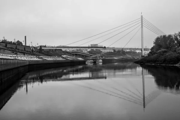 Gångbro över floden på stadens bakgrund. Flodvallen. — Stockfoto