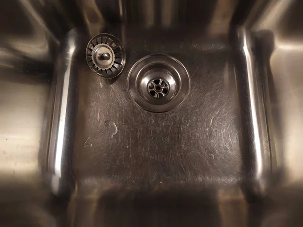 Shiny metal sink with a plug. Silver color. Scratch the surface. The view from the top at a slight angle. — Stock Photo, Image