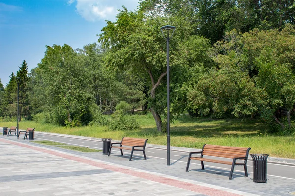 Çöp tenekeli ahşap banklar ve şehrin rıhtımında renkli tuğlalarla döşenmiş bir elektrik direği durağı..