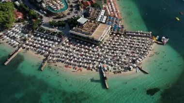 Arnavutluk 'un güneyinde Ksamil plaj şemsiyeleri ve turkuaz sularının havadan 4K drone görüntüsü.